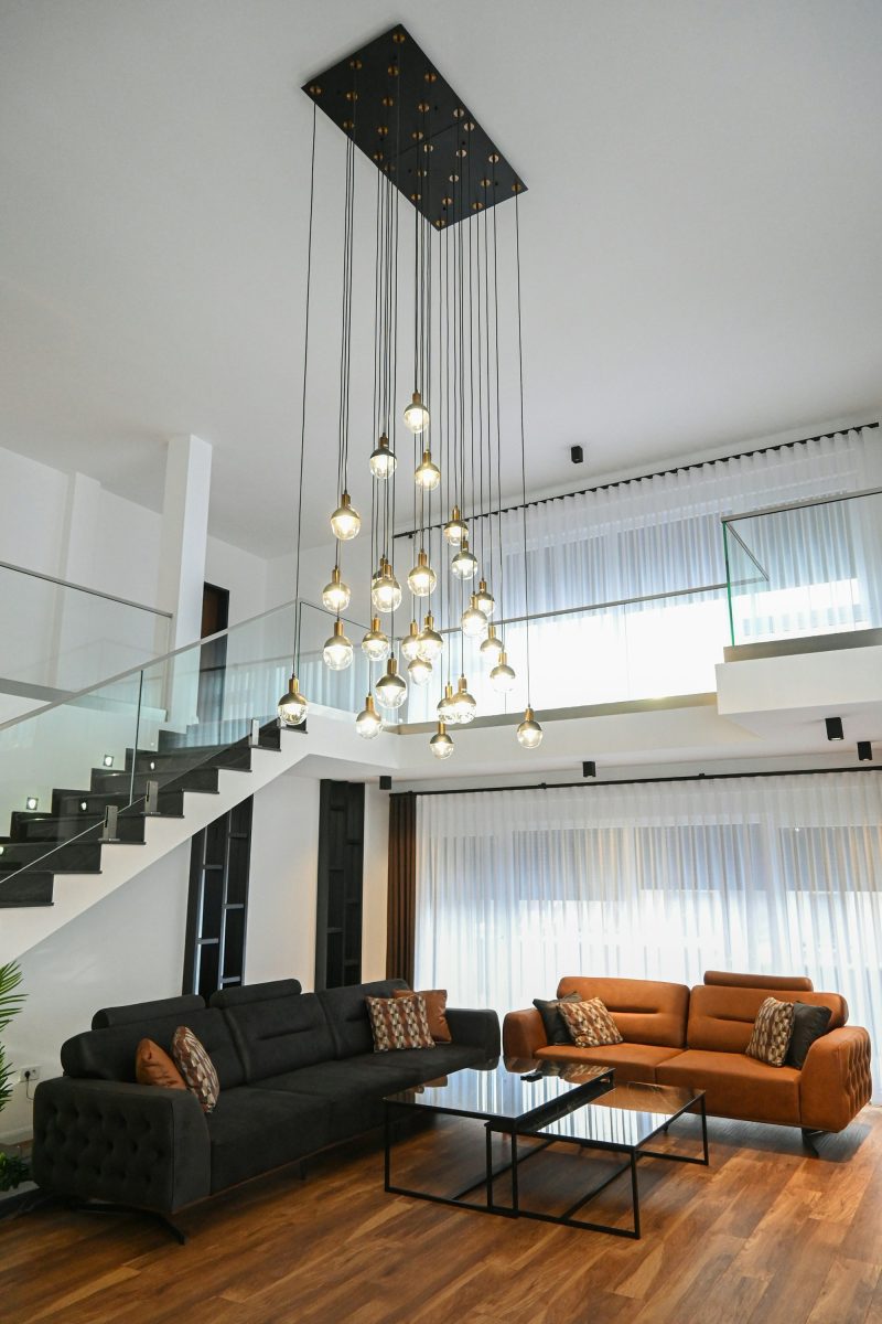 Double-height entrance with glass staircase and pendant chandelier